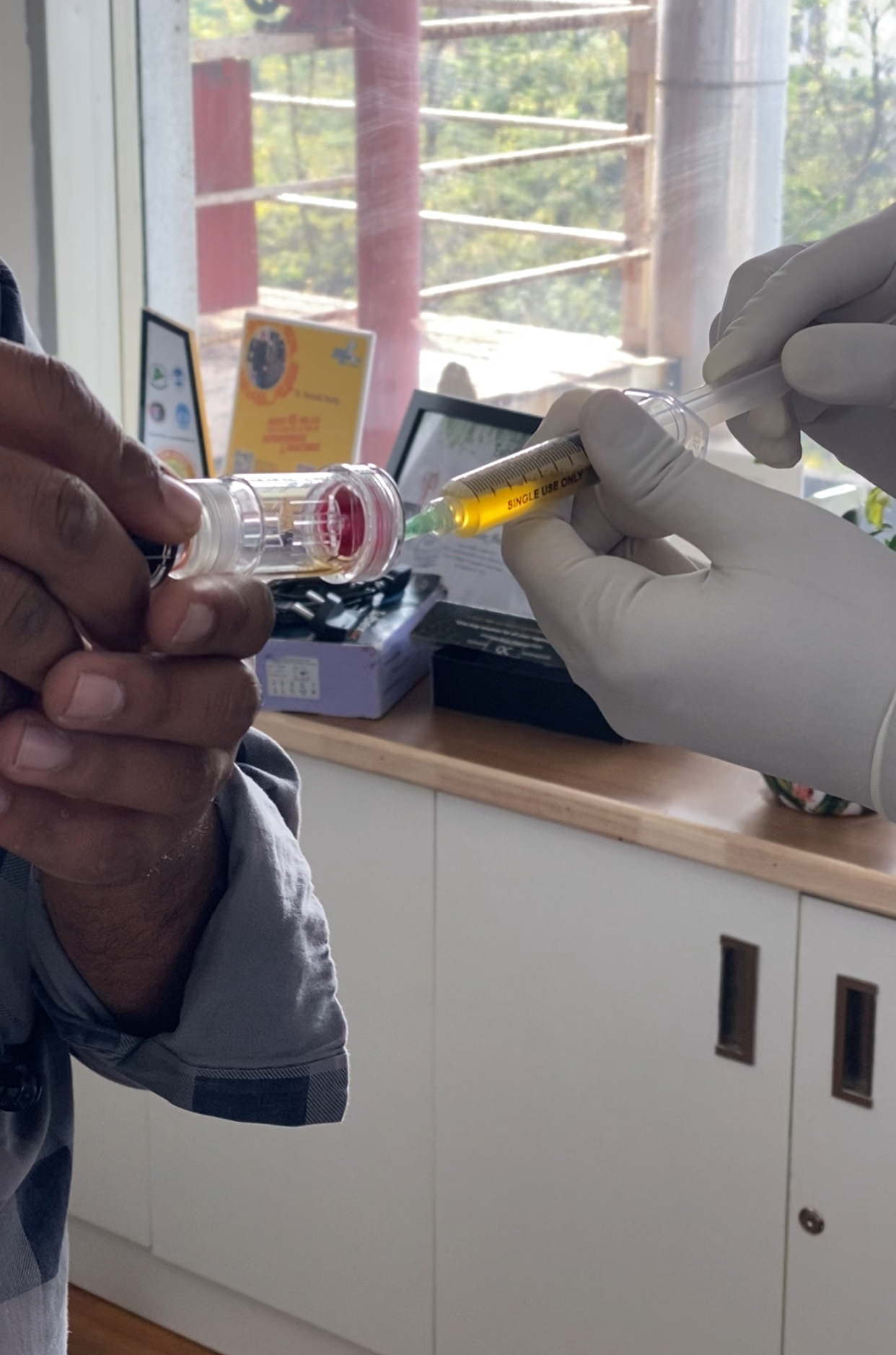Gloved hands preparing a syringe of yellow fluid for a clinical injection